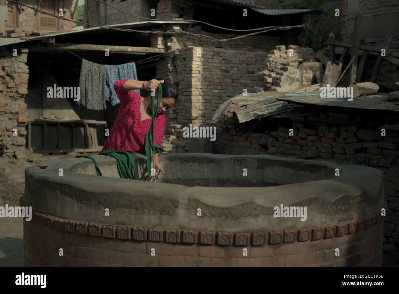 Una donna che prende acqua da un pozzo di acqua di comunità in una zona residenziale di Bhaktapur, Bagmati Pradesh, Nepal. Foto Stock