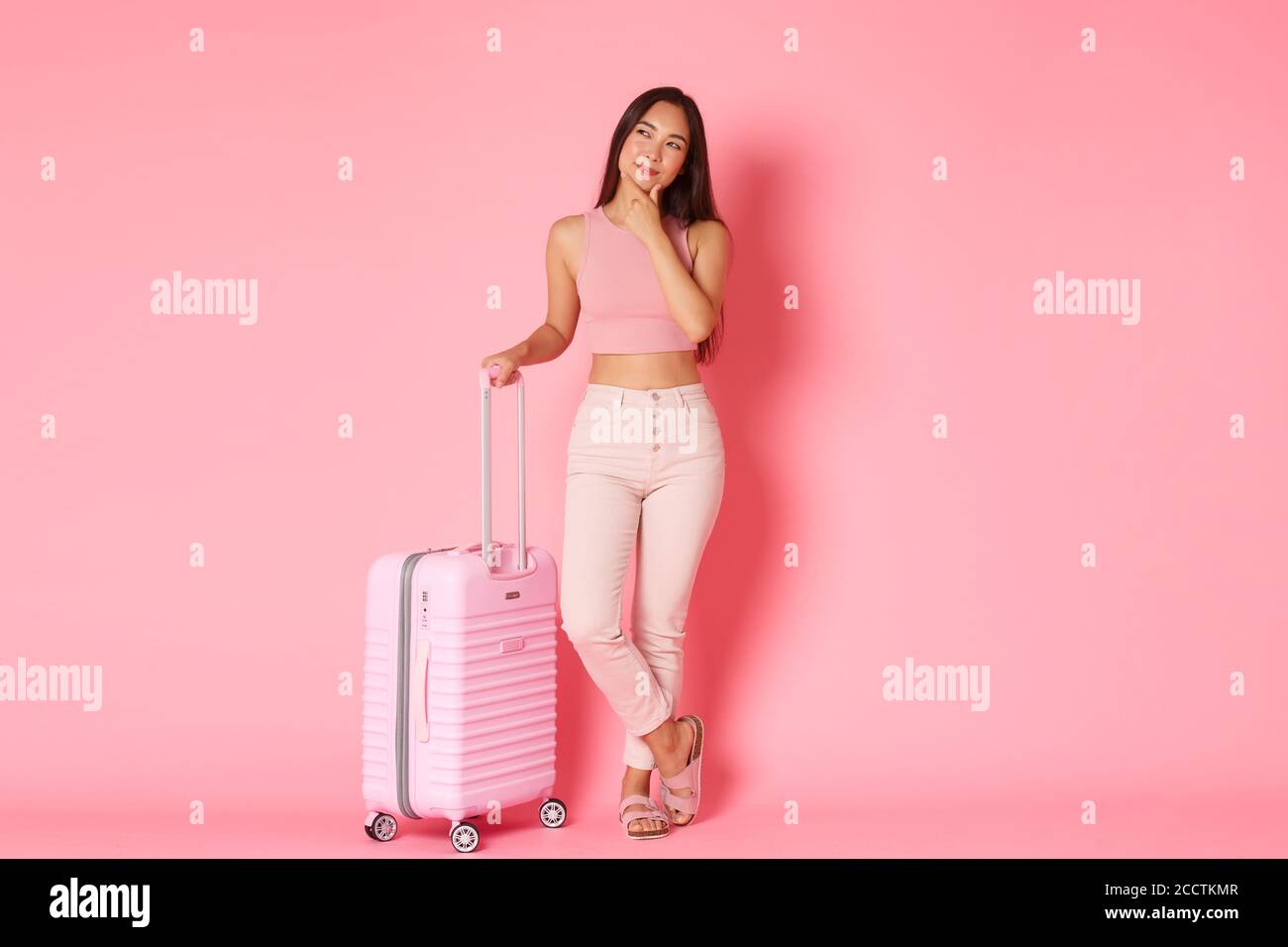 Viaggi, vacanze e vacanza. Intera lunghezza di bella ragazza asiatica pensierosa nella pianificazione di vestiti estivi dove andare, programma la rotta di volo Foto Stock