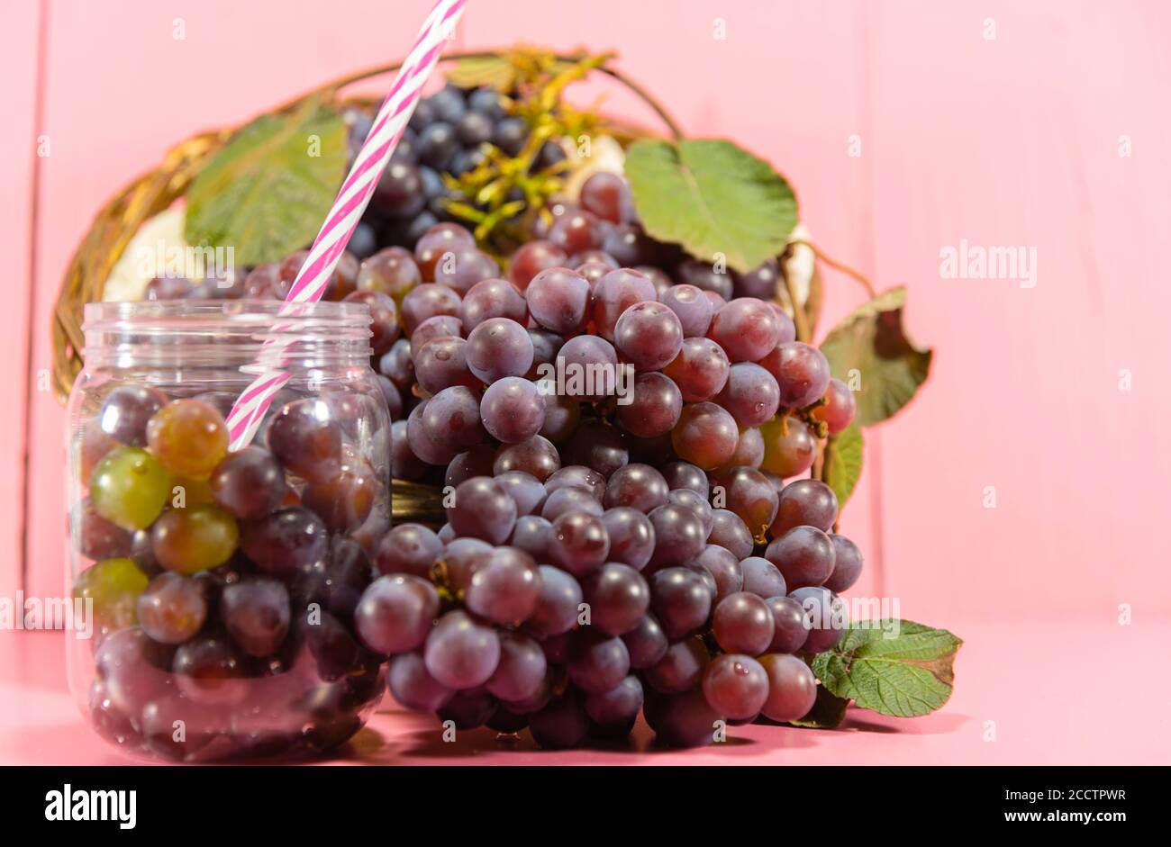 Pentola con grani e grappoli d'uva. Succo d'uva, bevanda rinfrescante. Bevanda di frutta. Ingrediente per vini e succhi. Frutta fresca. Uva rosa. Foto Stock