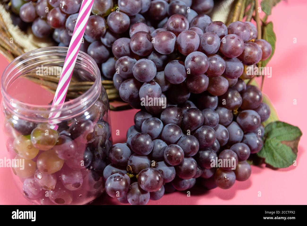 Pentola con grani e grappoli d'uva. Succo d'uva, bevanda rinfrescante. Bevanda di frutta. Ingrediente per vini e succhi. Frutta fresca. Uva rosa. Foto Stock