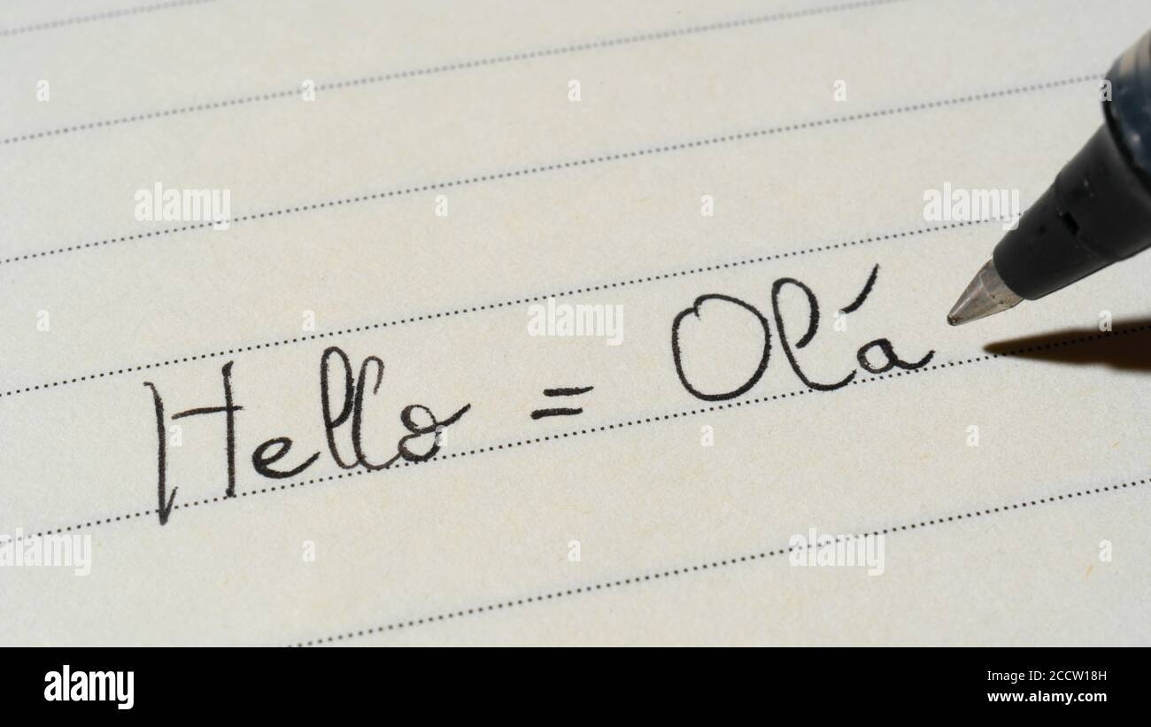 Principiante studente di lingua portoghese che scrive Ciao parola Ola per i compiti su uno scatto macro del notebook Foto Stock