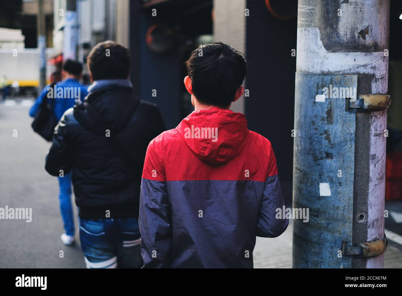 Giovani uomini che camminano sulla strada della città a Tokyo, Giappone Foto Stock