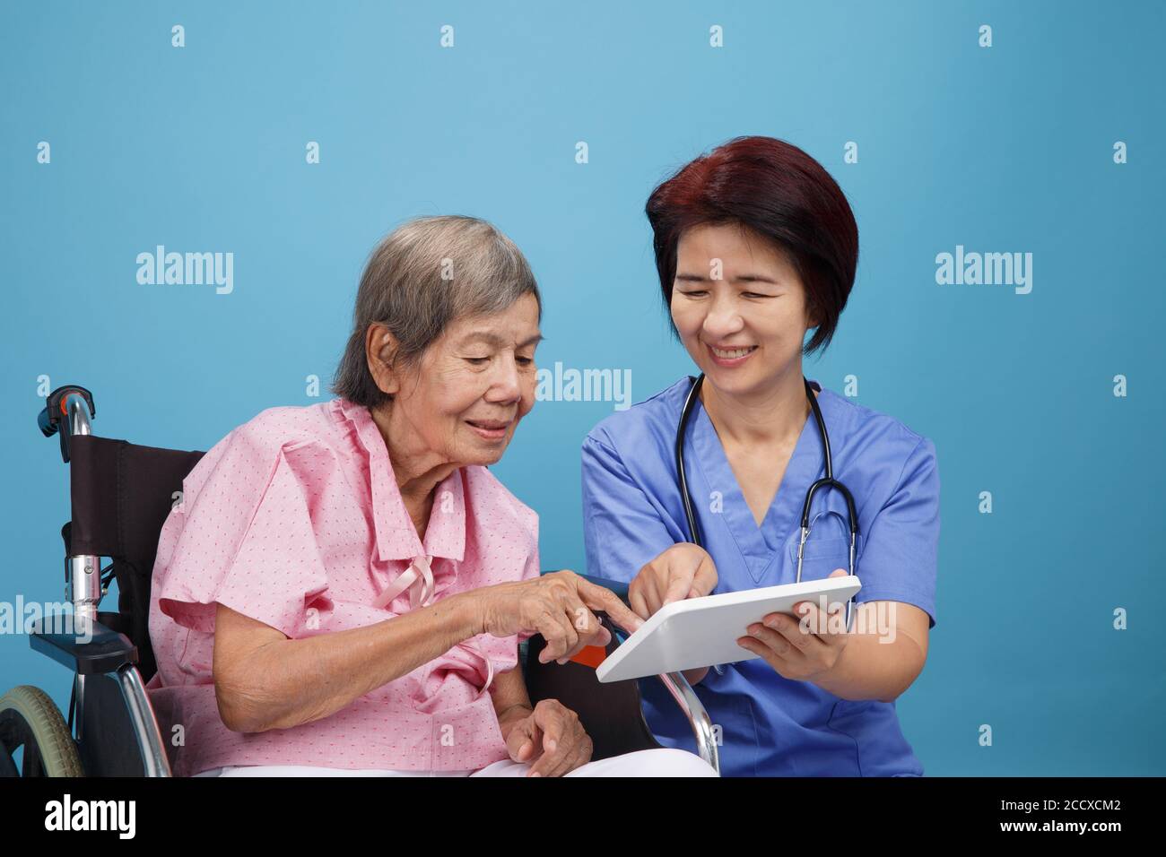 Infermiera asiatica che parla con la paziente anziana su sedia a rotelle Foto Stock