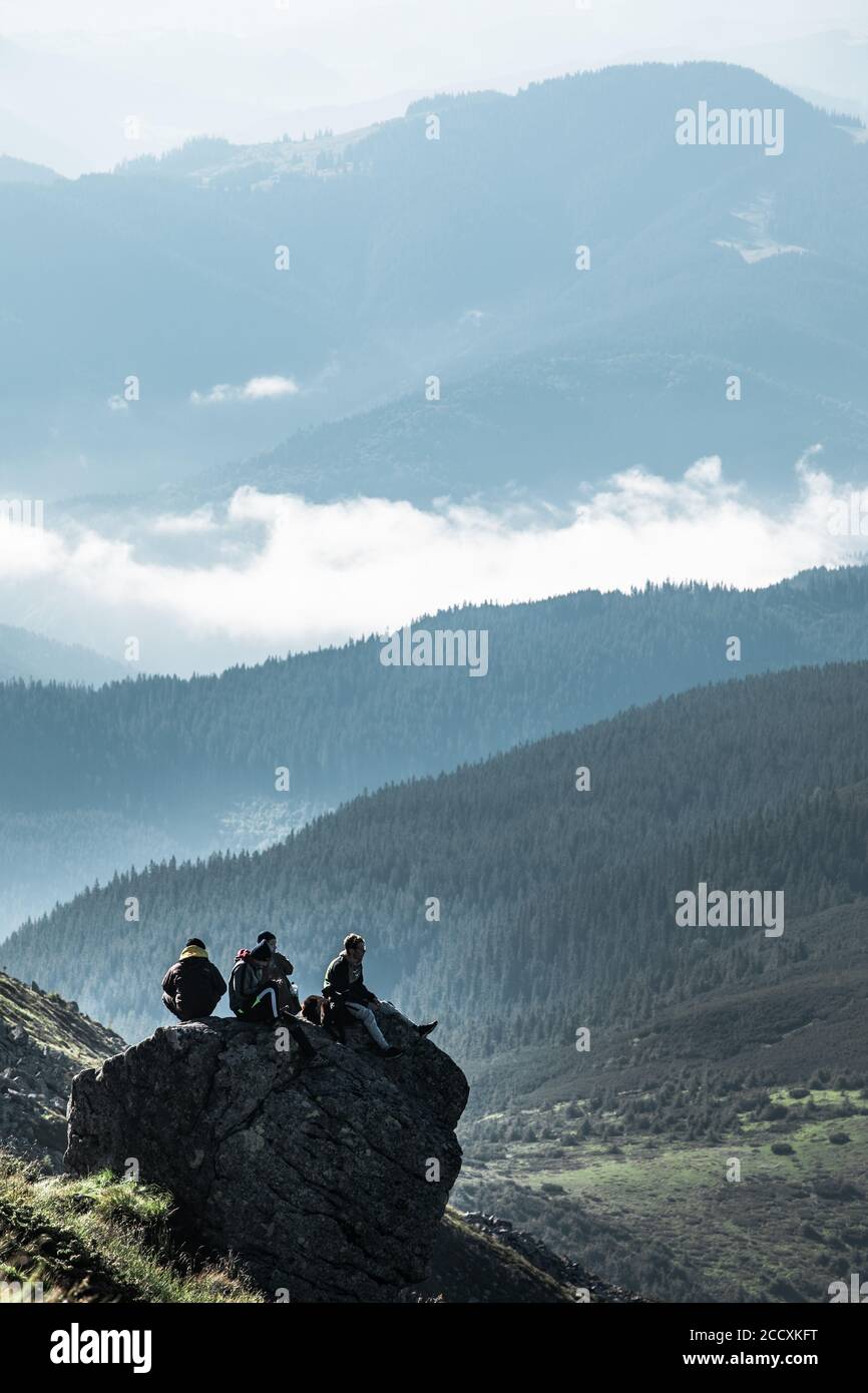 PIP Ivan, Ucraina - 2 agosto 2020: Amici di tre seduti sulla roccia in cima alla montagna godendo la vista Foto Stock