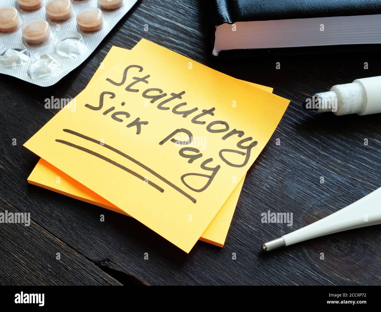 Un promemoria del Statutory Sick Pay SSP sulla pagina gialla sulla scrivania. Foto Stock