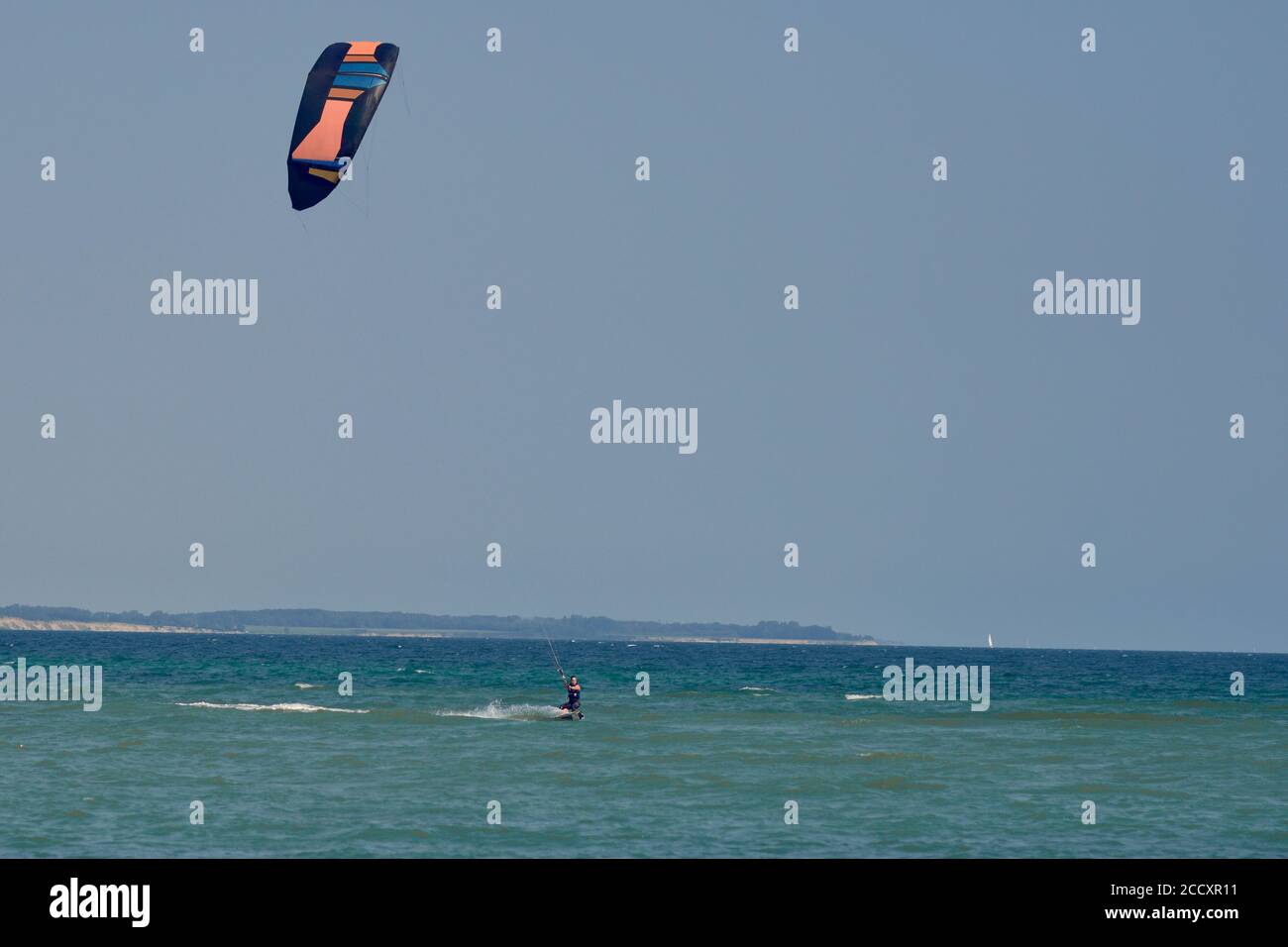 Bruna donna kitesurf o kite imbarco verso la fotocamera su una giornata estiva soleggiata in una vista frontale fotocamera Foto Stock