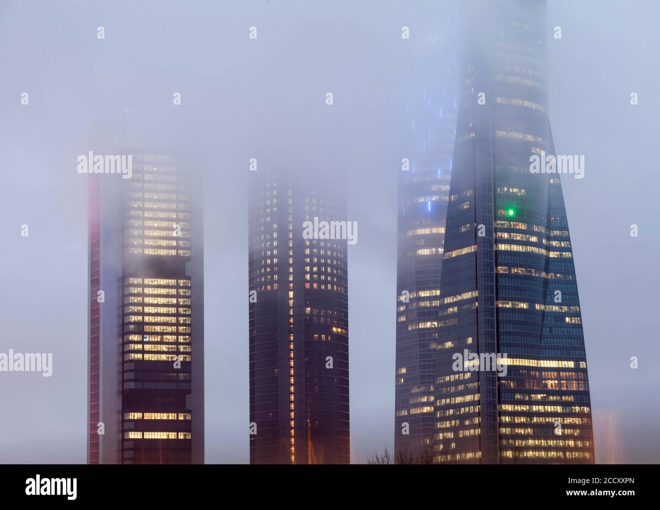 Cuatro Torres Business Area edificio illuminato in nebbia serale, Madrid, Spagna Foto Stock