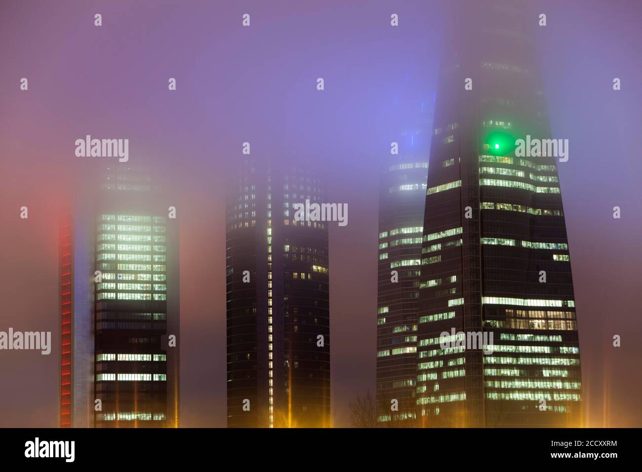 Cuatro Torres Business Area edificio illuminato in nebbia serale, Madrid, Spagna Foto Stock