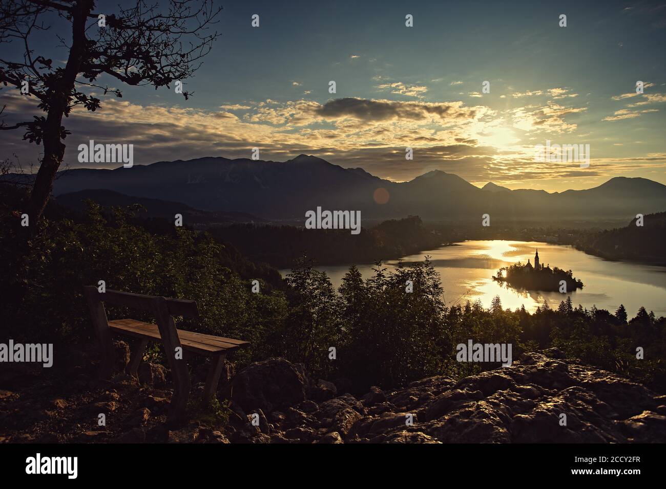Una panchina per gli amanti con vista sul sole che sorge sul lago di Bled, Bled, Slovenia Foto Stock