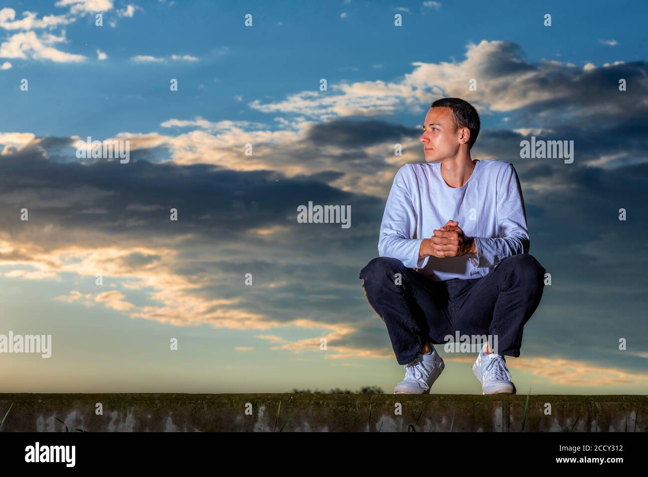 Uomo, 21 anni, seduto, al tramonto, Remstal, Baden-Wuerttemberg, Germania Foto Stock