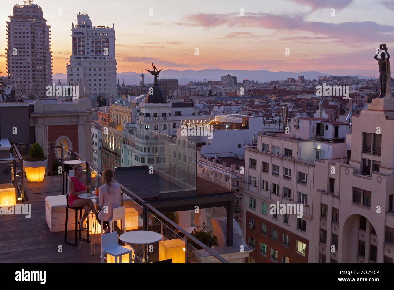 Due ragazze milleniali gustatevi un drink sulla terrazza di L'hotel Emperador con il paesaggio del centro cittadino di Madrid Foto Stock