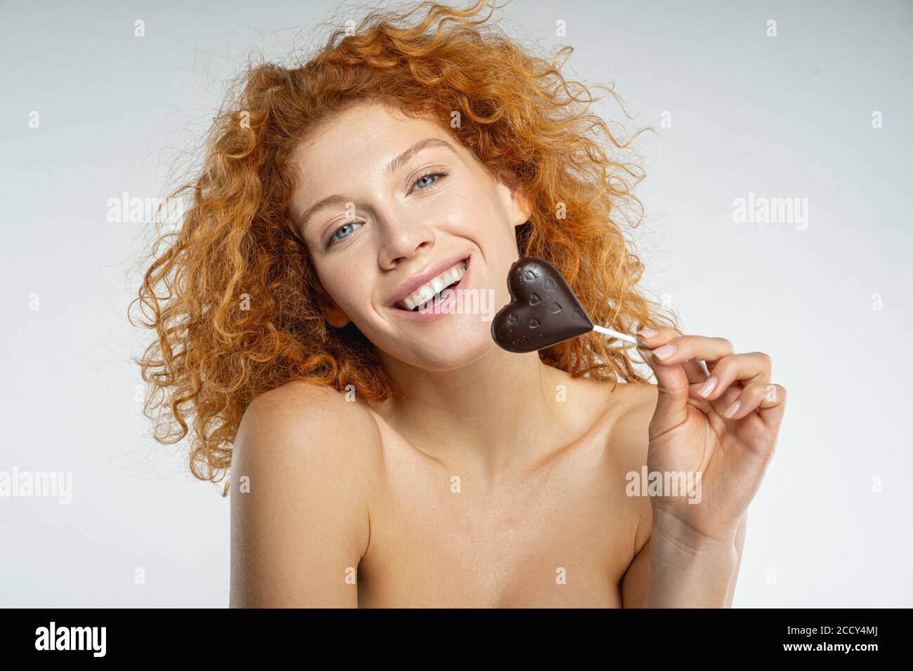 Allegra bella signora che tiene un lollipop a forma di cuore Foto Stock