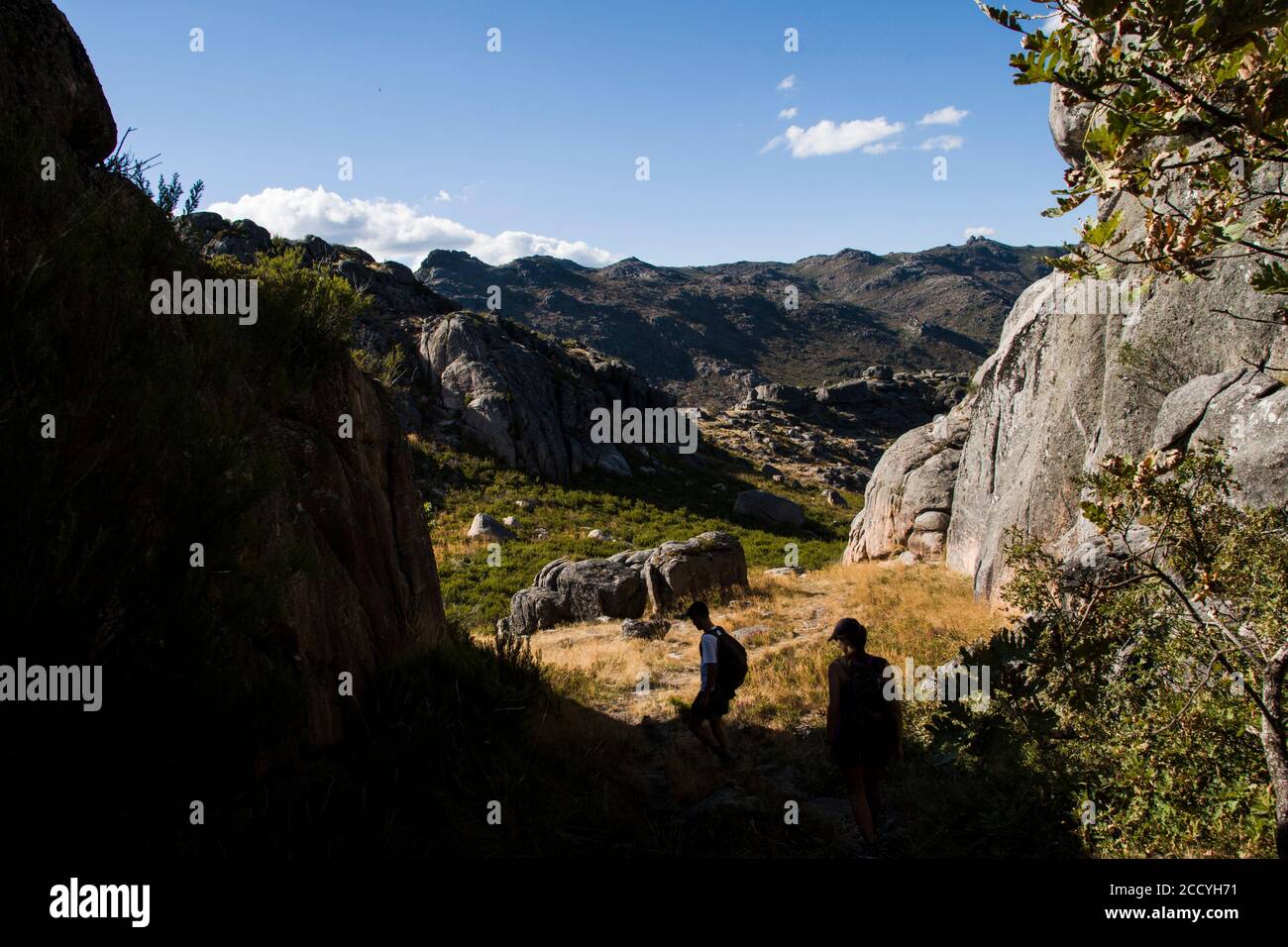 Escursionisti in controluce in discesa in un paesaggio di montagna su una giornata di sole Foto Stock