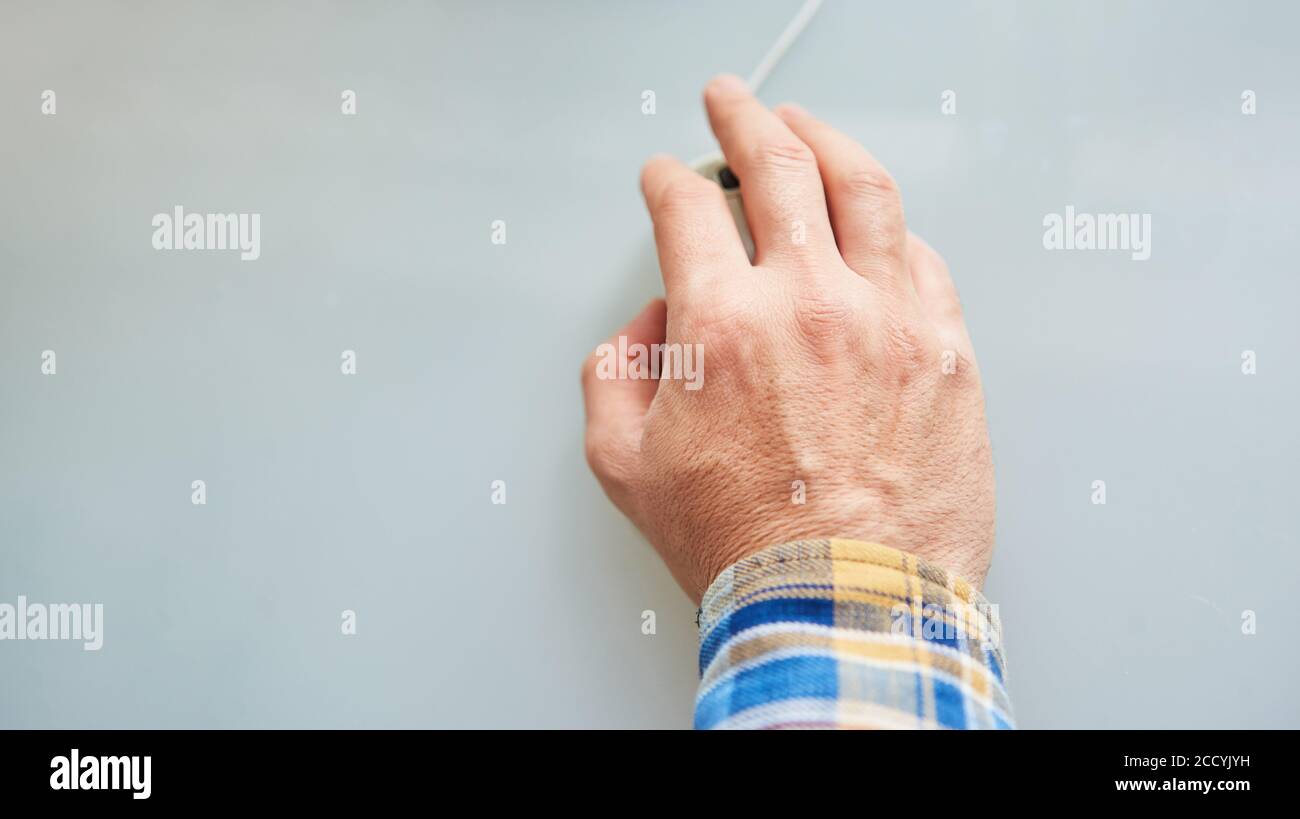 La mano di un anziano aziona un mouse del calcolatore in un classe computer Foto Stock