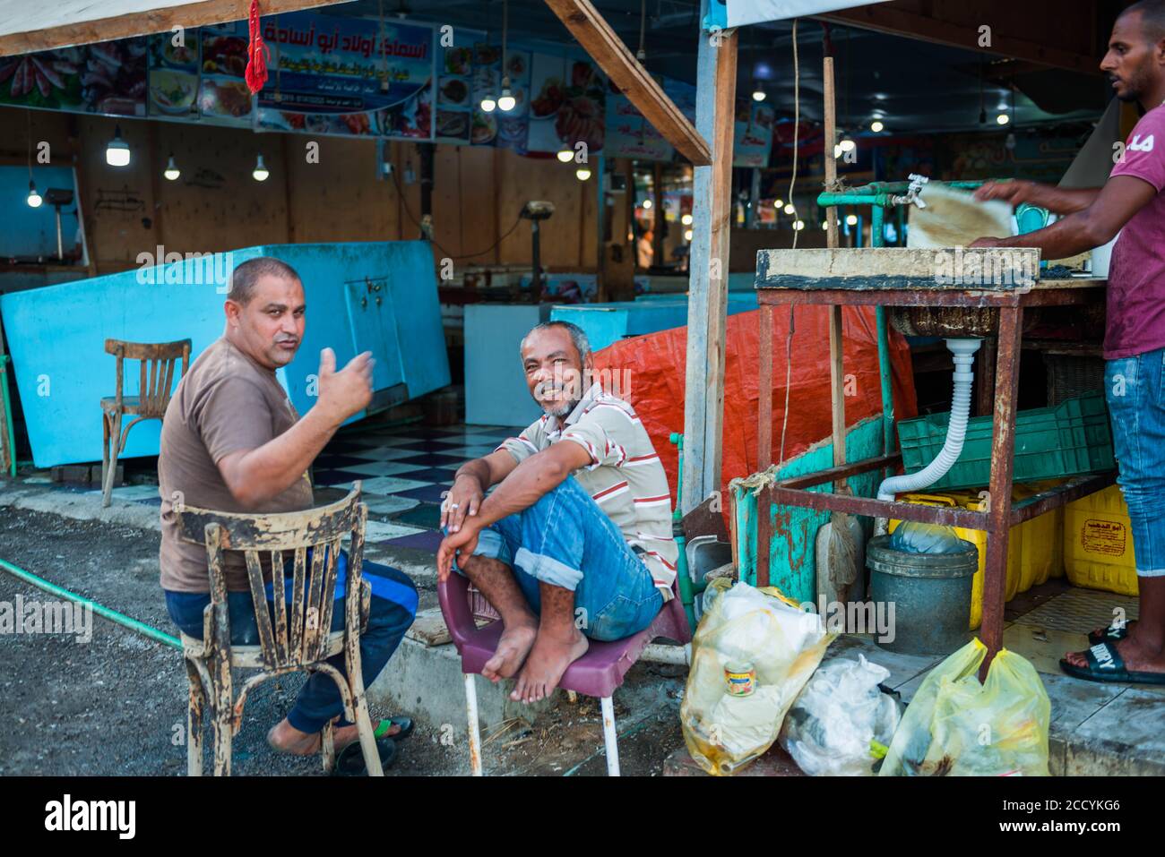 Egitto, Hurgada mercato del pesce lavoratori ritratti con costruzioni di costruzione sullo sfondo Foto Stock