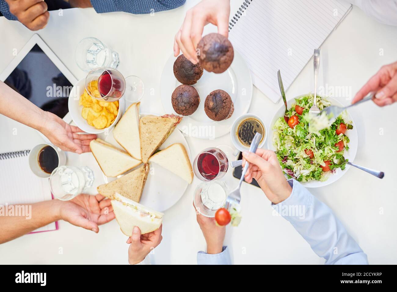 Gli uffici mangiano insieme panini e muffin come uno spuntino durante la pausa pranzo Foto Stock
