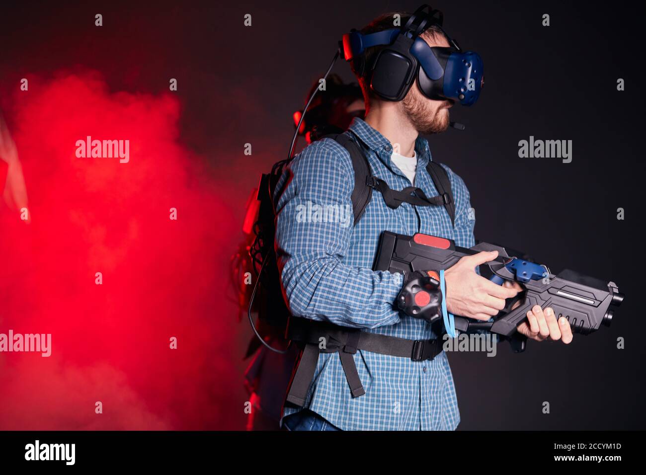 Guy che tiene il gioco di cecchino VR con la pistola per realtà virtuale e cuffie, occhiali. Retroilluminato al neon isolato Foto Stock