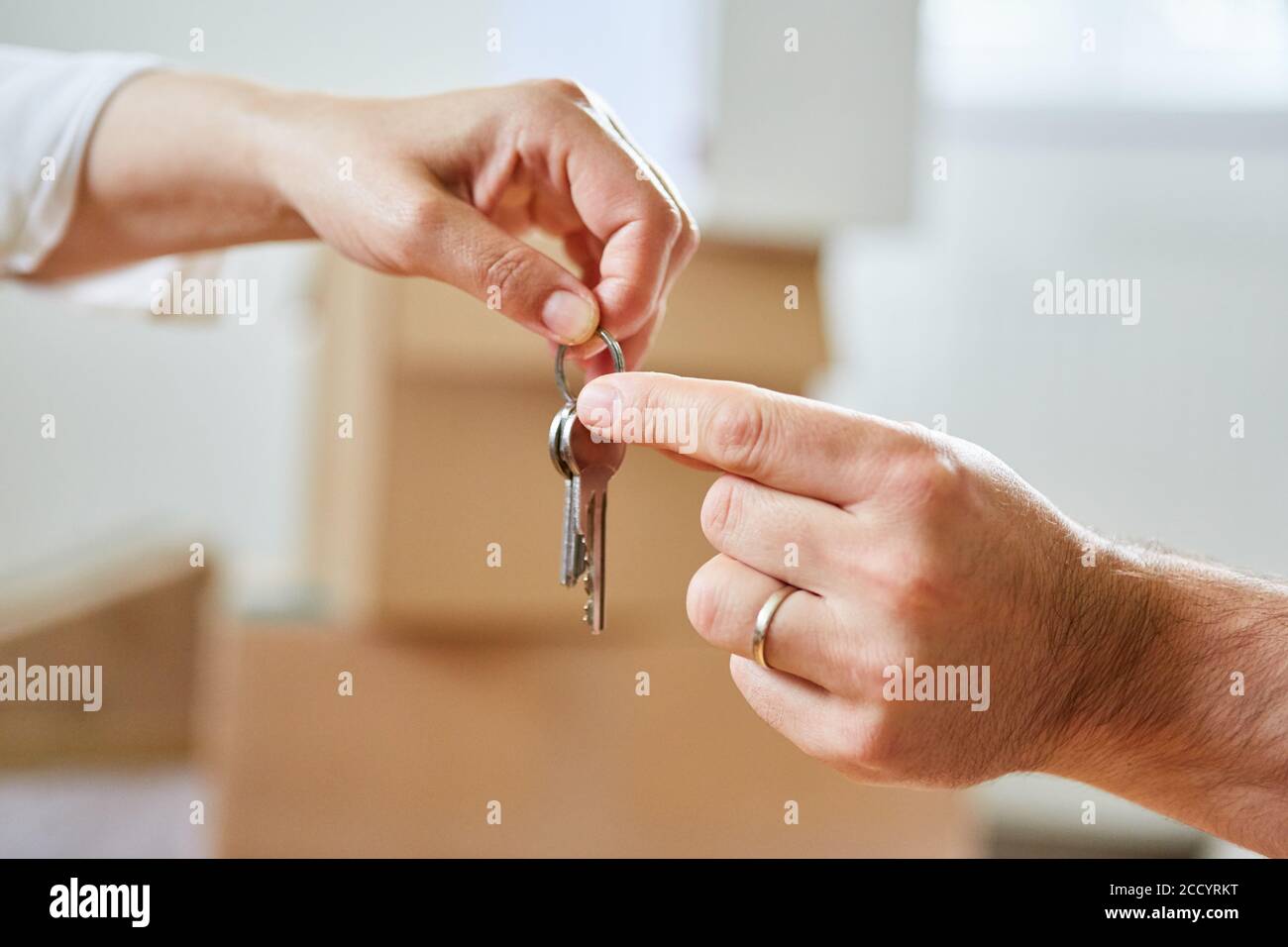 Due mani passano una chiave di casa come simbolo di acquisto di immobili e case Foto Stock