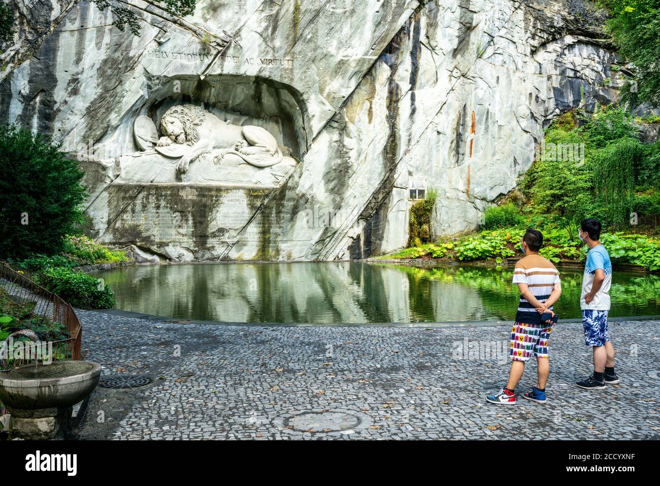 Lucerna Svizzera , 29 giugno 2020 : due turisti asiatici che indossano maschere chirurgiche che guardano il monumento del Leone di Lucerna durante l'estate 2020 e covid-19 c Foto Stock