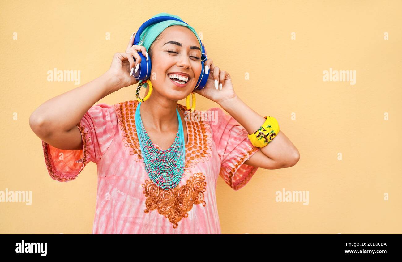Giovane donna africana che ascolta musica con cuffie dispositivo - ragazza felice che si diverte a ballare e cantare all'aperto - stile di vita, stile e tecnologia con Foto Stock