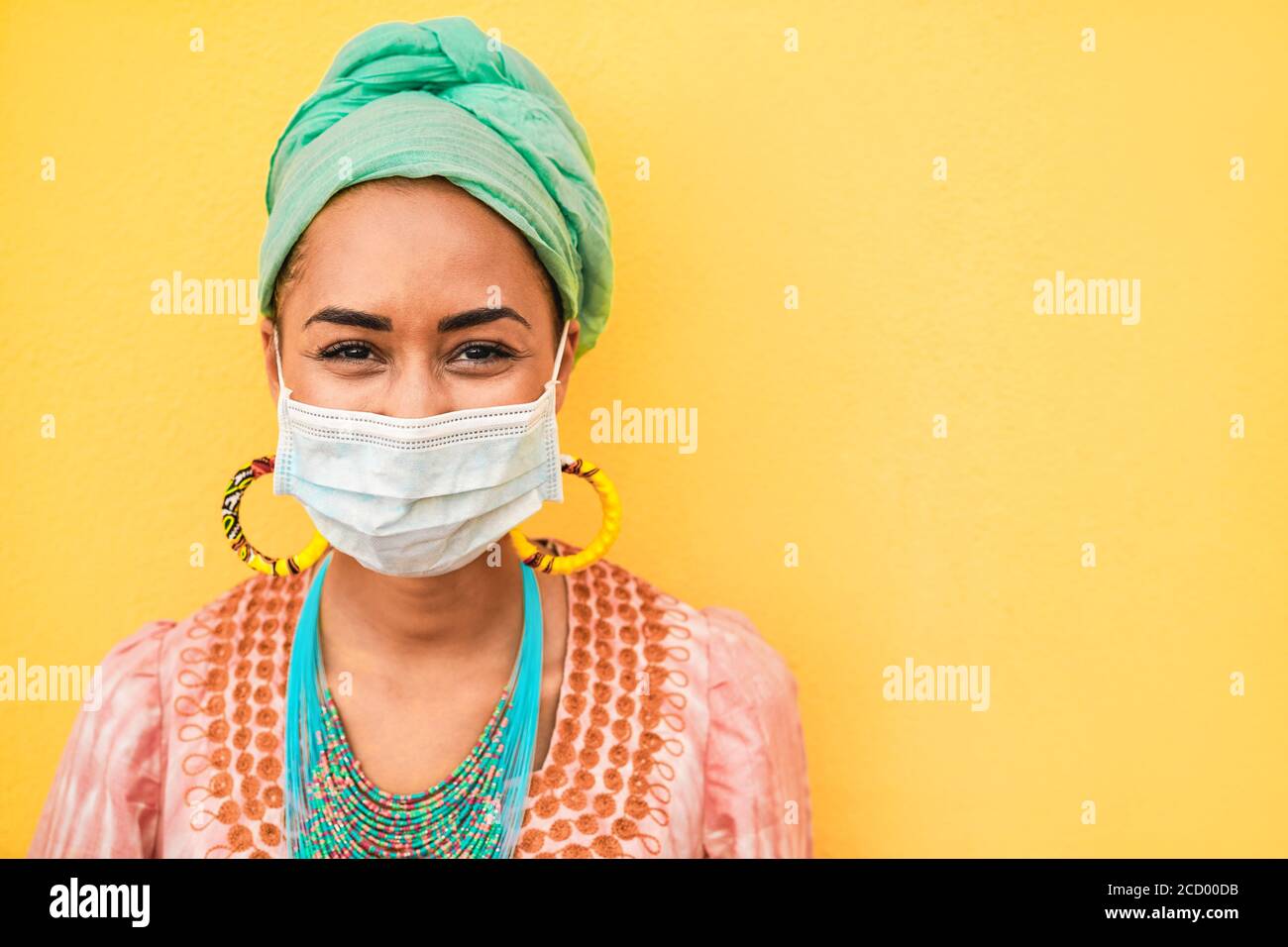 Ritratto di giovane donna africana che indossa una maschera protettiva per il viso - Ragazza felice che indossa abiti bohémien durante l'epidemia di coronavirus - etnica E Covid 19 l Foto Stock