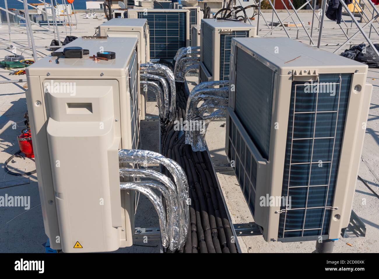 Unità di climatizzazione HVAC su un tetto di un nuovo edificio industriale con cielo blu e nuvole sullo sfondo. Foto Stock