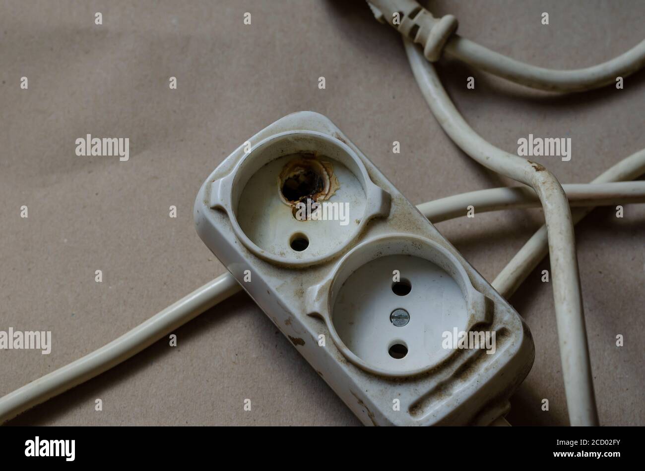 Condizione della spina elettrica, presa dopo scossa su fondo marrone. Presa multipla bianca dopo cortocircuito. Sicurezza elettrica. Foto Stock