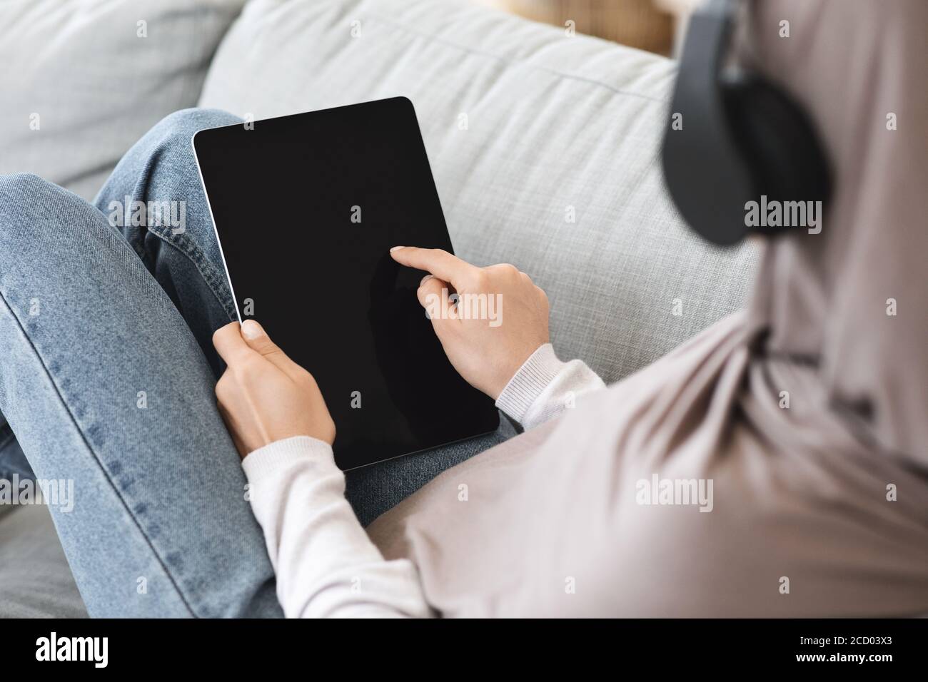 Donna irriconoscibile in hijab che usa un tablet digitale con schermo nero a casa Foto Stock