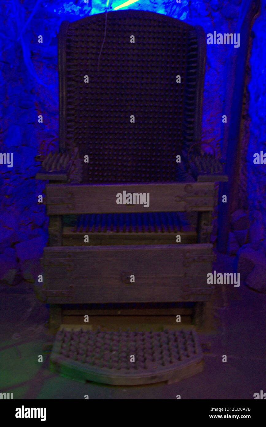 La sedia disprezzata di ferro usata per torture disumane con un strana luce blu dietro Foto Stock