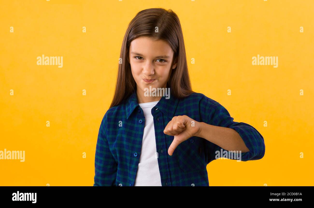 Giovane ragazza teenage che mostra i pollici verso il basso gesto Foto Stock