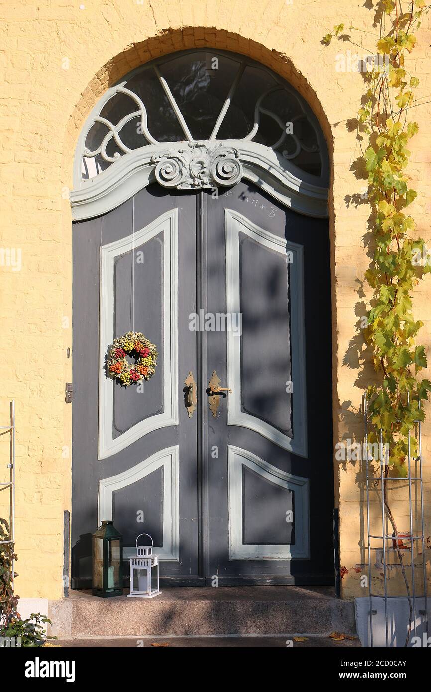 Scatto verticale di una grande porta d'ingresso con un Natale decorazione appesa su di esso Foto Stock