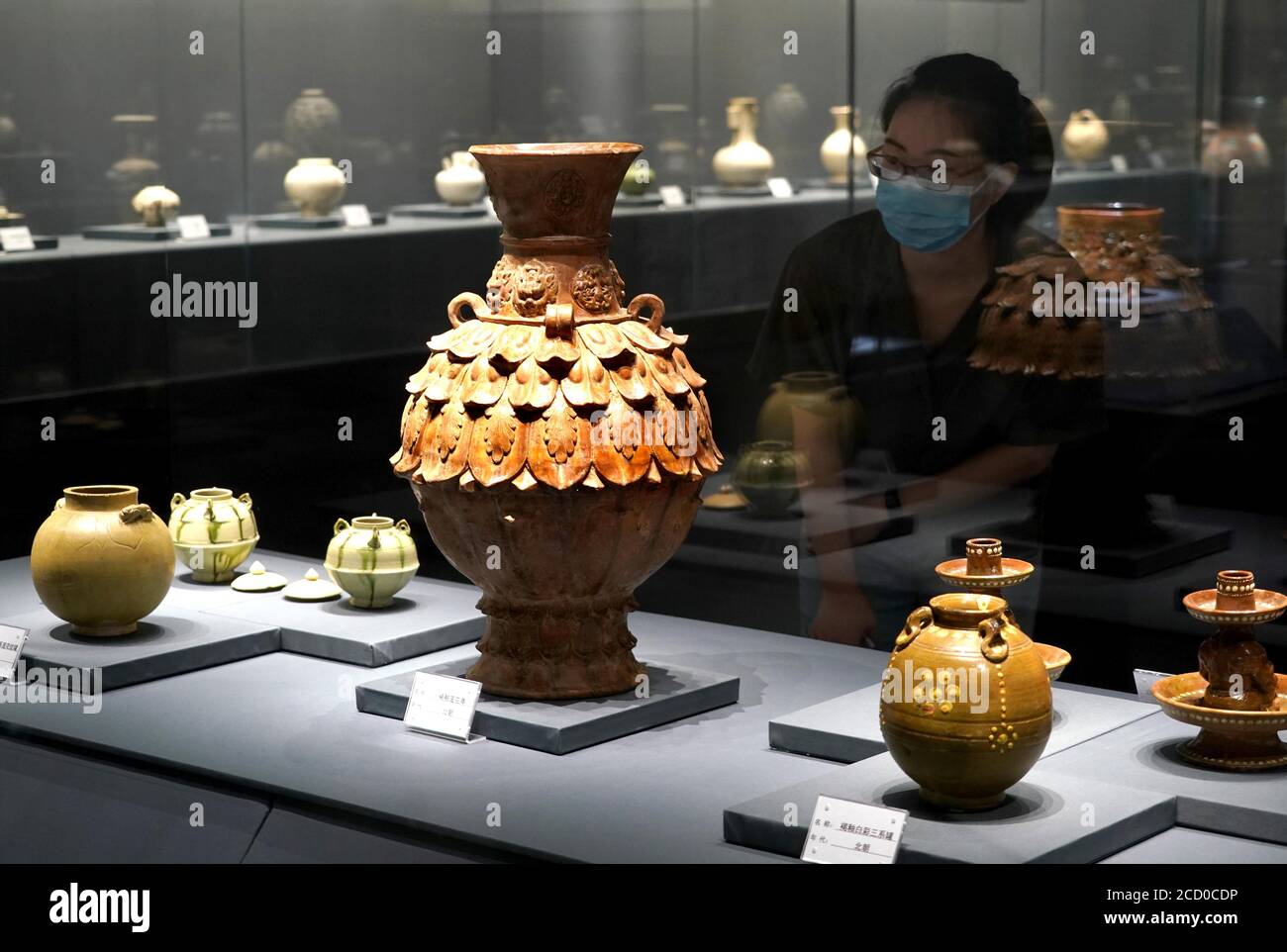 Zhengzhou, provincia cinese di Henan. 25 Agosto 2020. Un visitatore guarda le mostre durante una mostra di ceramica a Zhengzhou, provincia centrale di Henan, 25 agosto 2020. La mostra di ceramiche, che comprende più di 100 mostre scoperte lungo il bacino del fiume giallo dai tempi antichi, è iniziata martedì a Zhengzhou. Credit: Li An/Xinhua/Alamy Live News Foto Stock