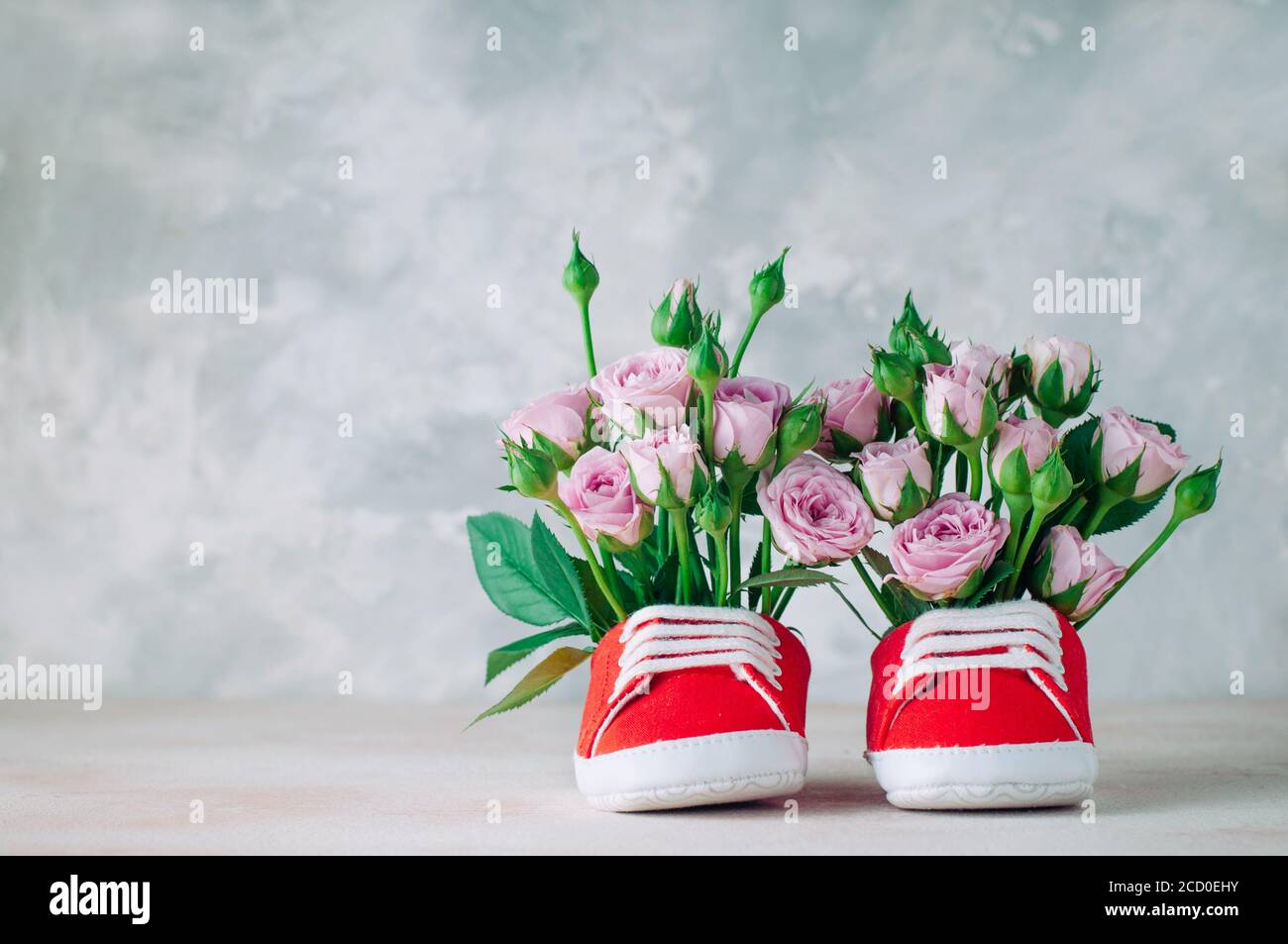 Paio di scarpe rosse per bambini riempite con fiori di rose. Spazio vuoto  per il testo Foto stock - Alamy