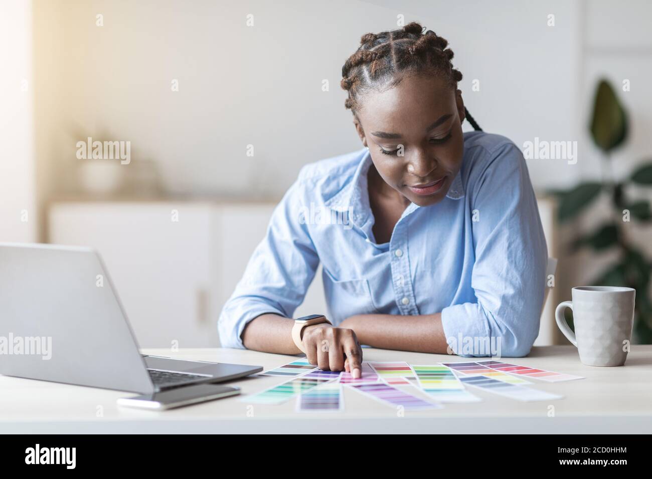 Young African Female Interior Designer Checking Colour Swatch for New Progetto Foto Stock