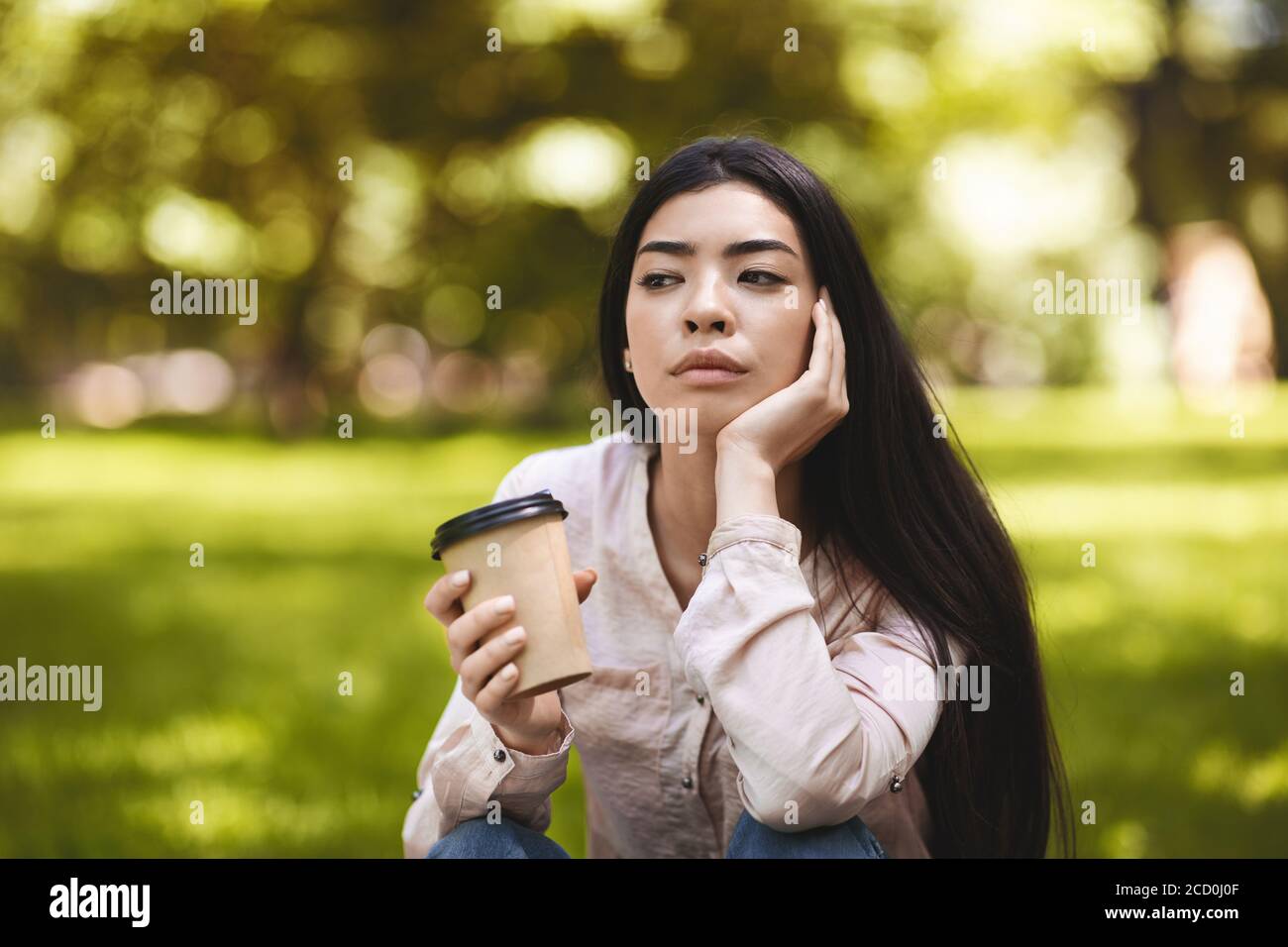 Pausa caffè all'aperto. Pessive Asian Girl godendo di un drink Takeaway al Park Foto Stock