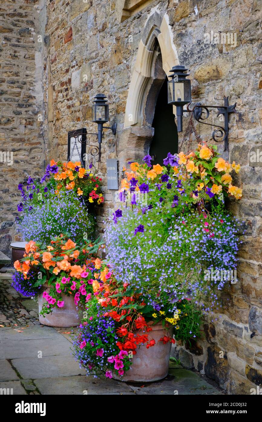 Cestini appesi e mostre floreali all'esterno dell'ingresso del Lord Crewe Arms in Blanchland Northumberland Foto Stock