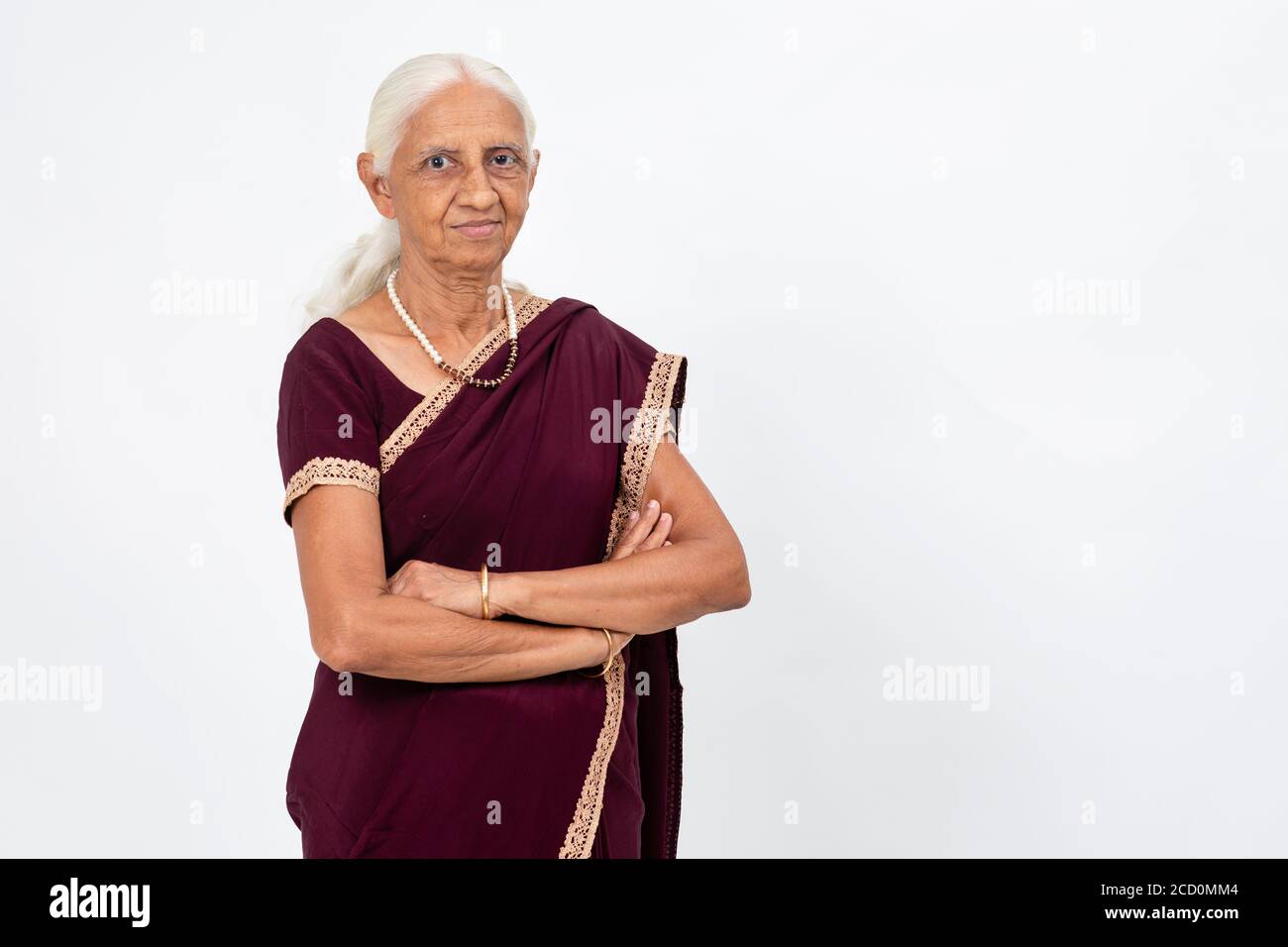 Anziana donna indiana in piedi con le braccia piegate. Donna anziana sorridente e guardando nella fotocamera Foto Stock