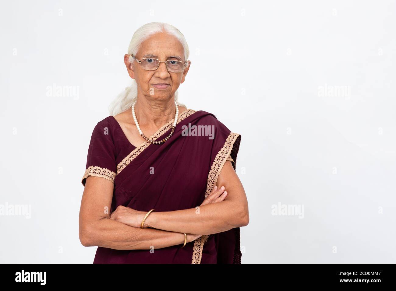Anziana donna indiana in piedi con le braccia piegate. Donna anziana sorridente e guardando nella fotocamera Foto Stock