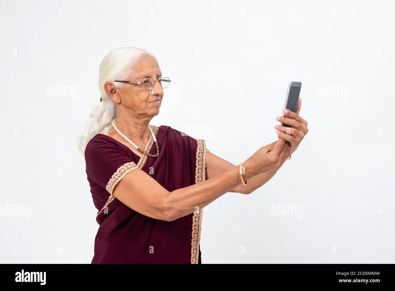 La signora indiana matura prende un selfie dal suo telefono. Donna anziana che usa il suo telefono cellulare per scattare una foto. Foto Stock