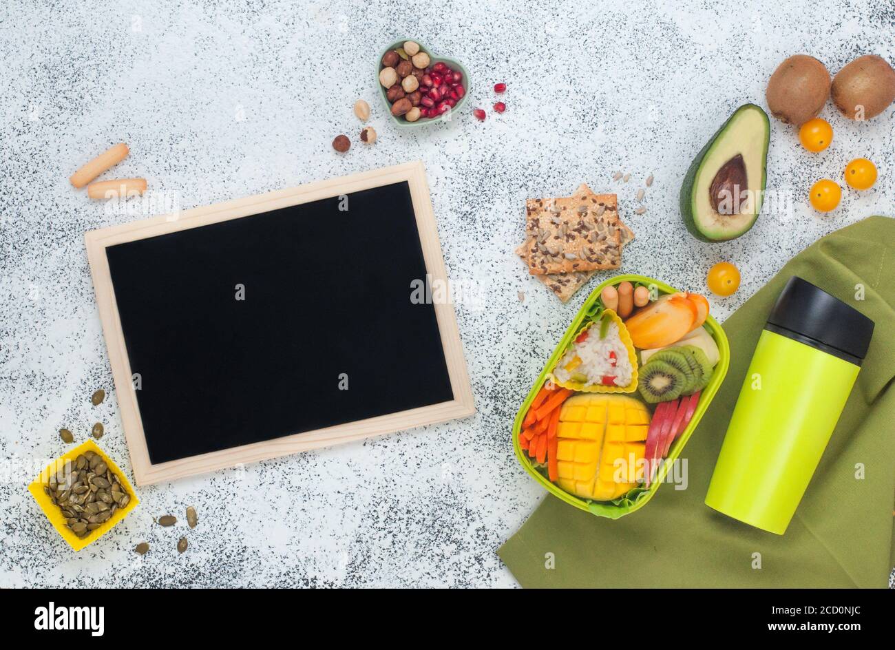 Pranzo al sacco con riso, frutta fresca e verdure, thermo tazza e vuoto bordo nero gesso sullo sfondo grigio con spazio vuoto per il testo; vista dall'alto, f Foto Stock