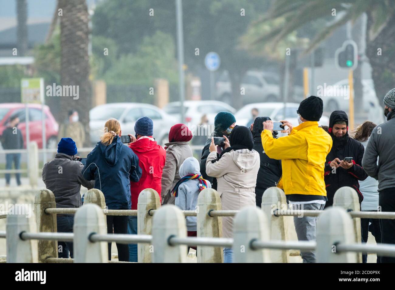 Gruppo di persone vestite di abbigliamento invernale che fotografano un evento meteorologico durante una tempesta a Città del Capo, Sud Africa Concept clima e stagioni Foto Stock