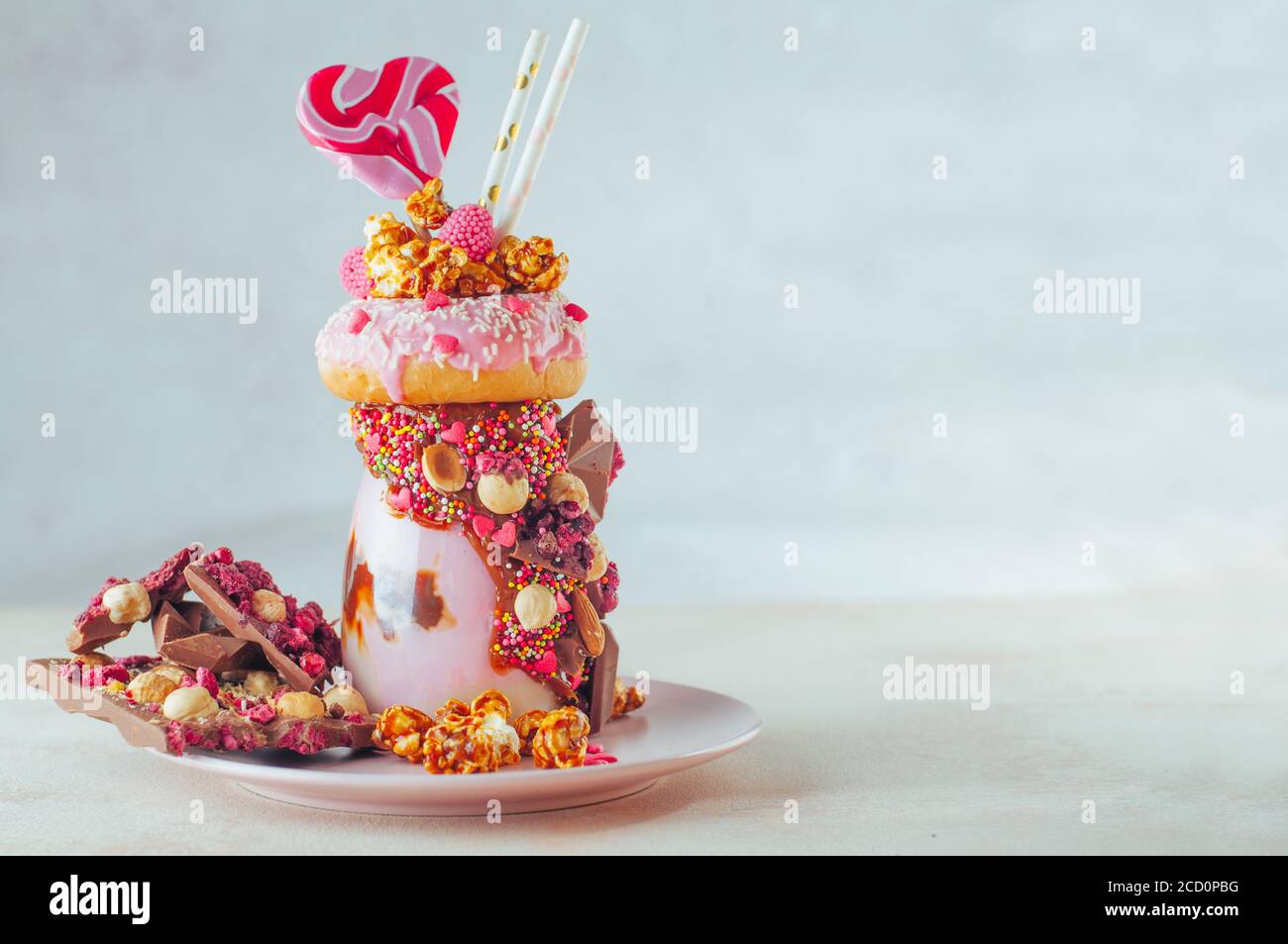 Raspberry Freak agita con ciambella, popcorn e dolci su sfondo grigio con spazio di copia; fuoco selettivo. Foto Stock