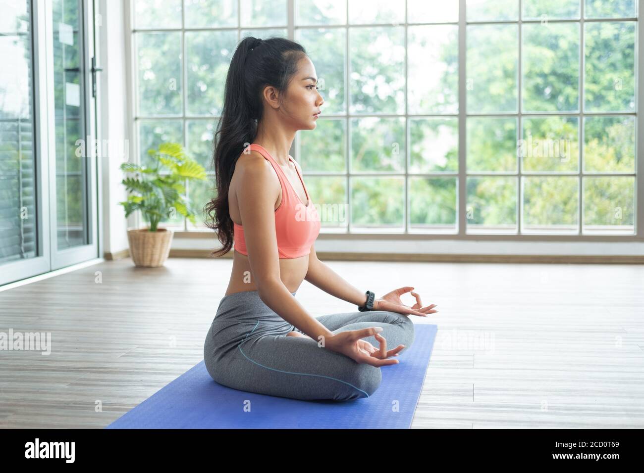 Giovane donna asiatica che fa esercizi di yoga a casa, seduta in facile con meditare, respirare e rilassarsi. Foto Stock