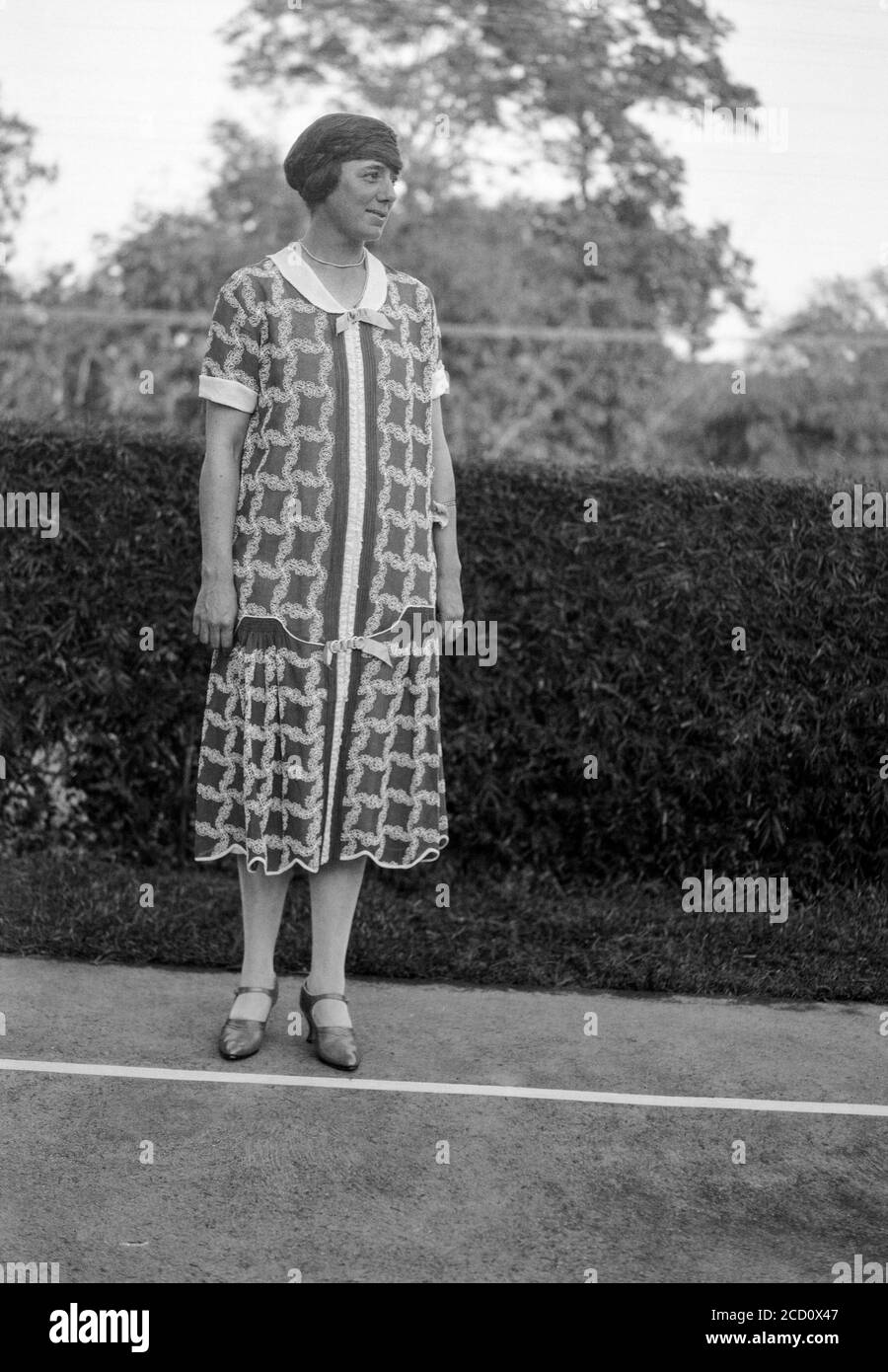 Vintage 1920 fotografia inglese in bianco e nero che mostra una giovane donna, fuori, in posa in abiti alla moda del giorno. Foto Stock