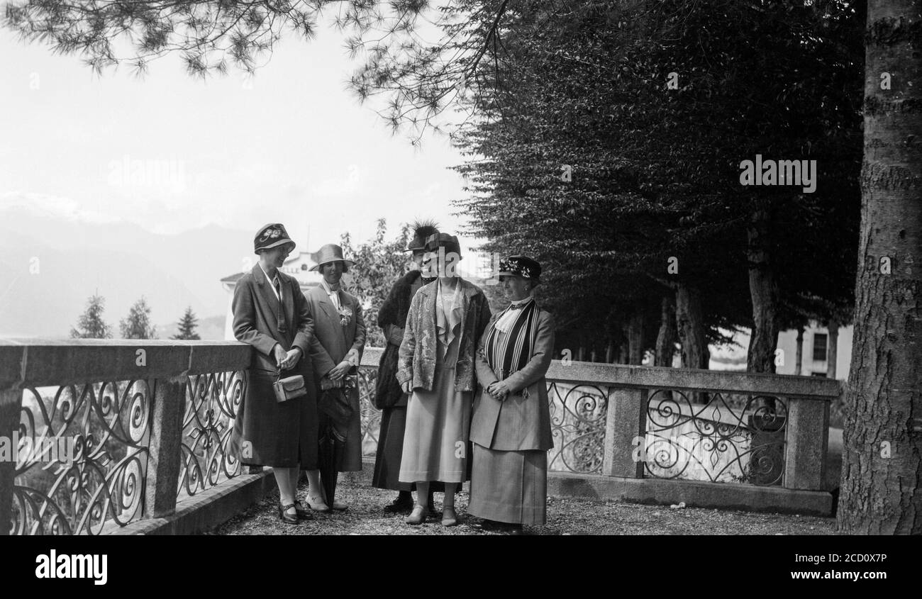 Una fotografia in bianco e nero degli anni '20 che mostra un gruppo di turisti inglesi di diverse età che si rilassano e posano per la telecamera sul balcone di un edificio in Svizzera. Foto Stock