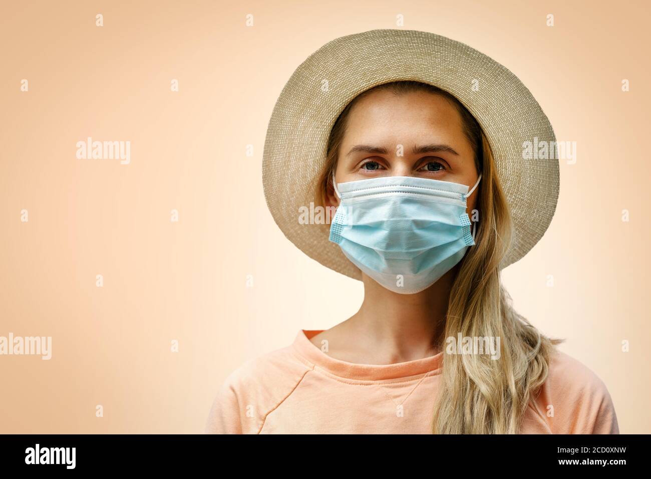 ritratto di giovane donna che indossa una maschera medica protettiva su sfondo arancione pastello. concetto pandemico coronavirus Foto Stock