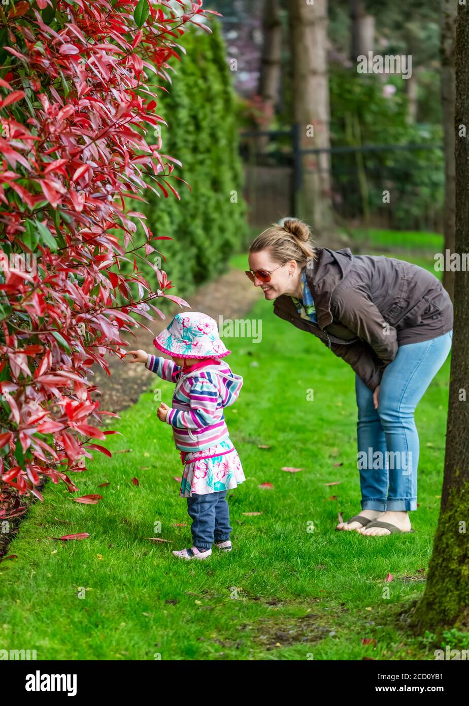 Madre e figlia che guardano il fogliame nel parco in una giornata di riposo in primavera; Surrey, British Columbia, Canada Foto Stock