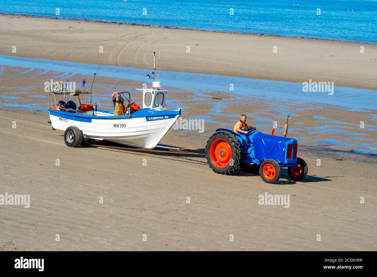 Granchio o aragosta, pescatore che guida un trattore che trasporta la loro barca fuori dal mare Redcar Cleveland UK Foto Stock