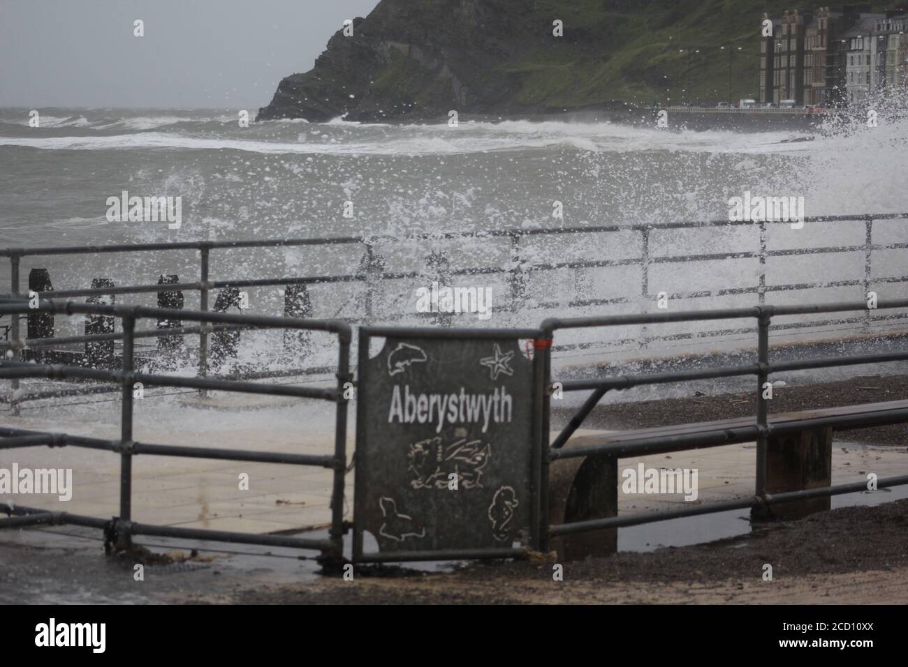 Aberystwyth Wales UK Weather 25 agosto 2020 : forti piogge e venti di Gale Force battter regioni costiere del Galles, forti venti guidare in enormi onde che sconfinano contro le difese marine di Aberystwyth. I vacanzieri coraggiosi venti di forza gale durante una passeggiata pomeridiana tempesta lungo la passeggiata, Credit: mike davies/Alamy Live News Foto Stock