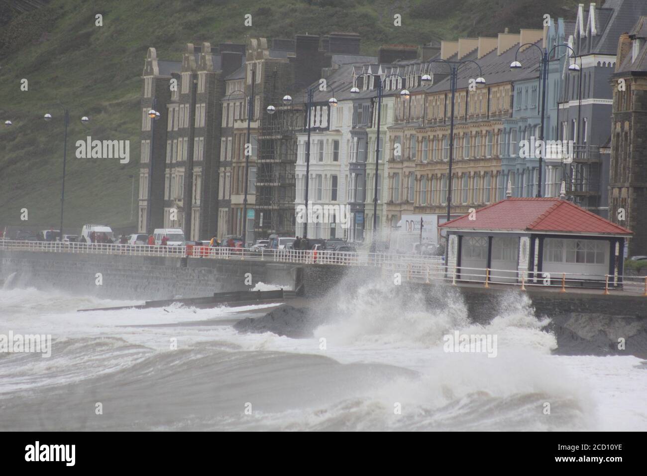 Aberystwyth Wales UK Weather 25 agosto 2020 : forti piogge e venti di Gale Force battter regioni costiere del Galles, forti venti guidare in enormi onde che sconfinano contro le difese marine di Aberystwyth. I vacanzieri coraggiosi venti di forza gale durante una passeggiata pomeridiana tempesta lungo la passeggiata, Credit: mike davies/Alamy Live News Foto Stock